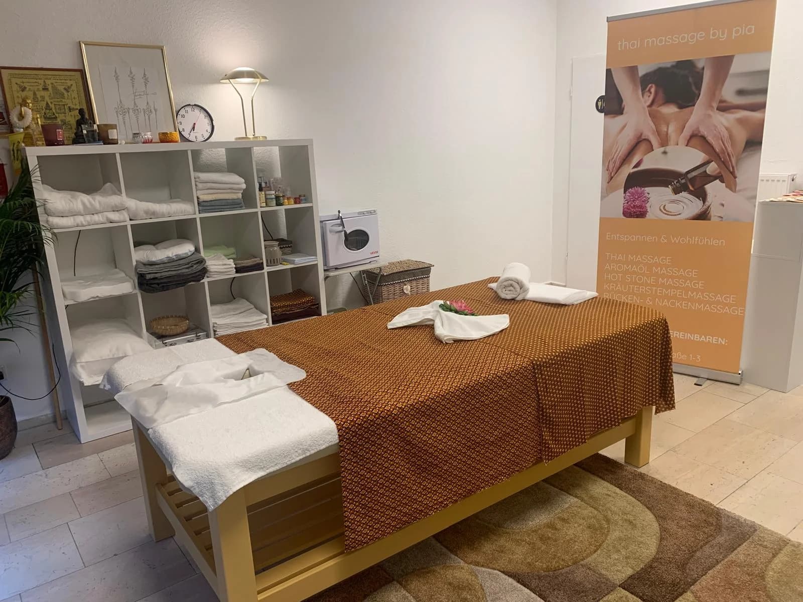Massageliege mit Handtüchern und Blüte im Behandlungsraum