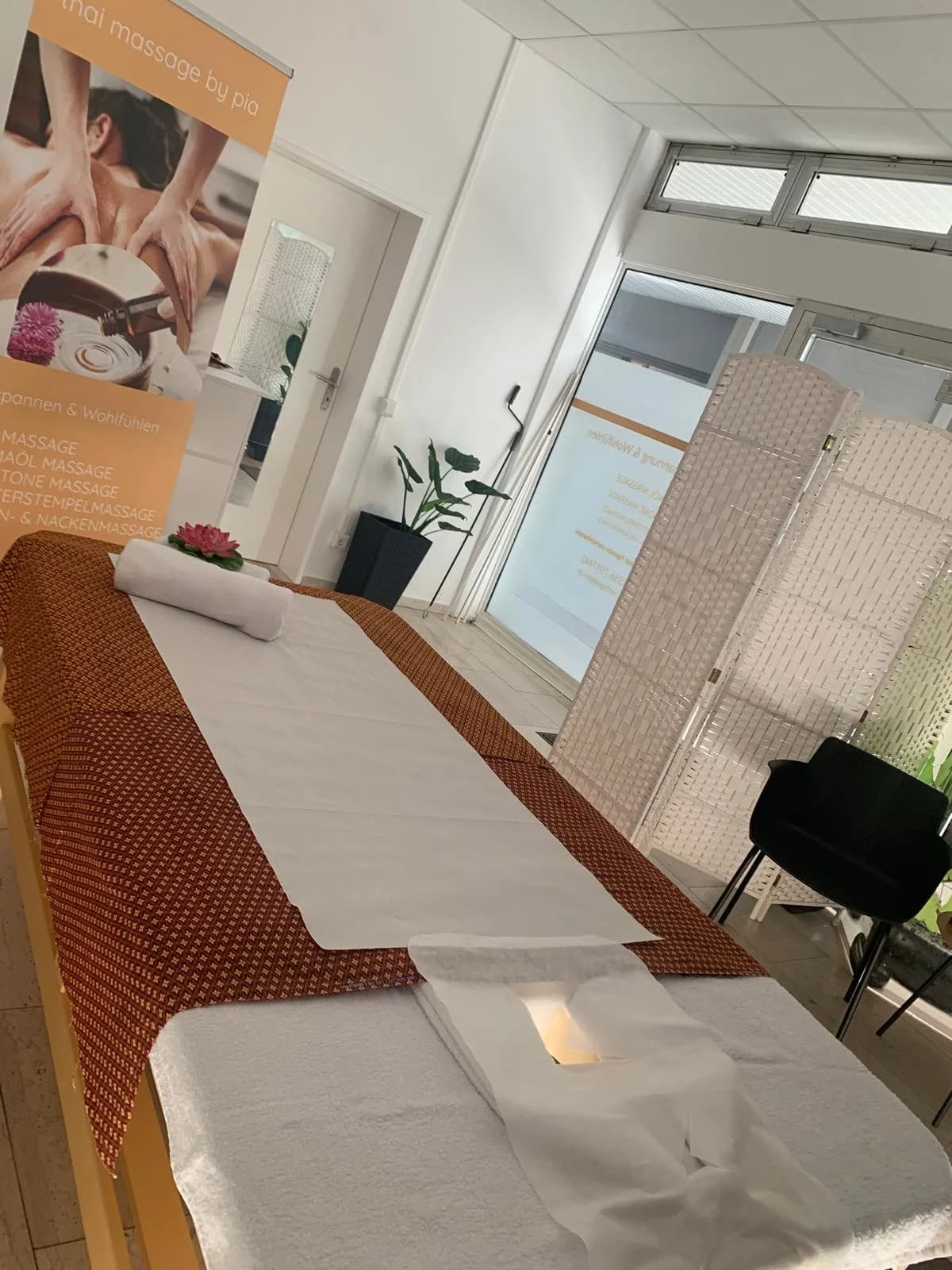 Ruhiger Behandlungsraum mit Massageliege und Vorhängen