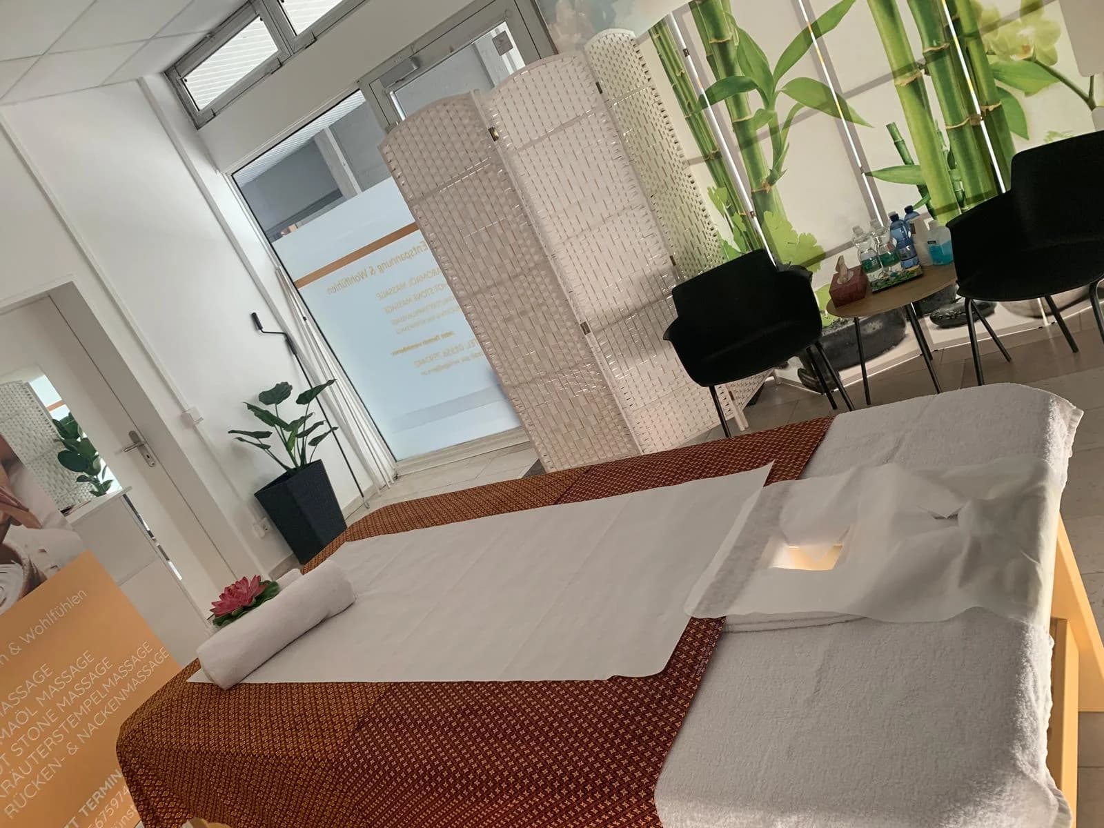 Ruhiger Behandlungsraum mit Massageliege und Vorhängen